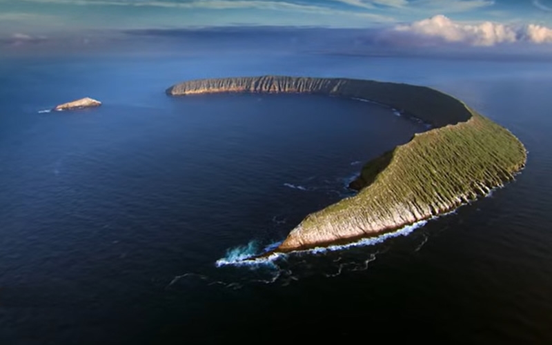 Aerial view of one of the Galapagos Islands, shaped like a crescent or the high side of part of a volcanic crater..