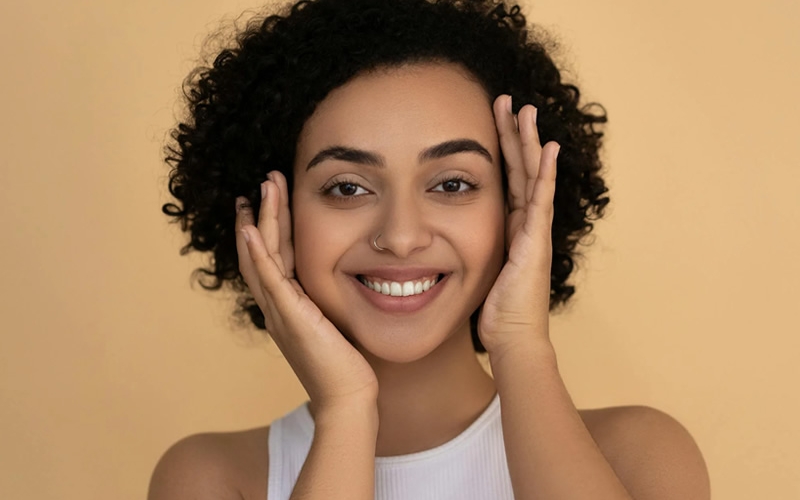 Woman in white tank top smiling.